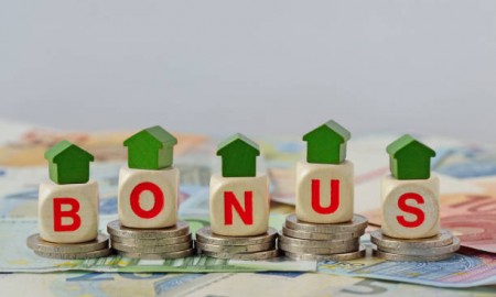 Wooden house and blocks with the word Bonus on coins and banknotes - Concept of home renovation bonus