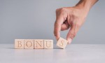 Businessmen wear a white shirt at their desks in the office. Use your hand to pick up a wooden cube inscribed with the word bonus.